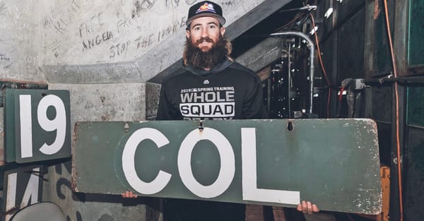 Blackmon holds a COL sign from the Fenway Park scoreboard. He’s wearing a black hoodie.