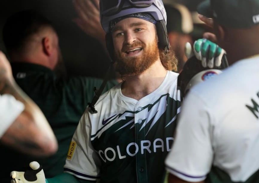 Rodgers celebrates in the dugout after a home run. He’s wearing the purple rally ski helmet.