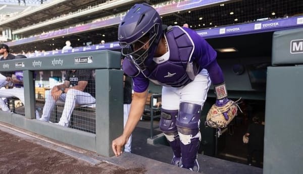 Díaz leaves the dugout wearing purple catchers gear, including a purple helmet.