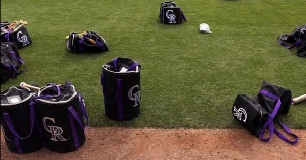 Rockies gear bags are scattered on the outfield grass.